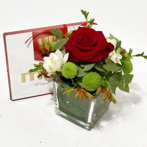 Flower arrangement in a glass vase and Merci candy box